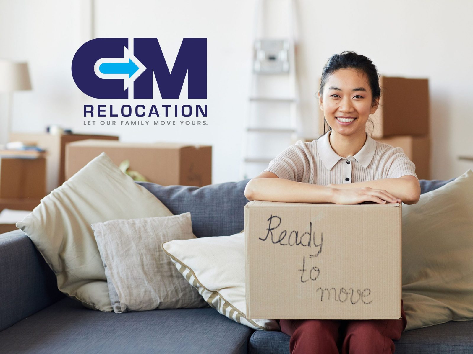 Smiling woman moving abroad alone, leaning on a box labelled “Ready to move”